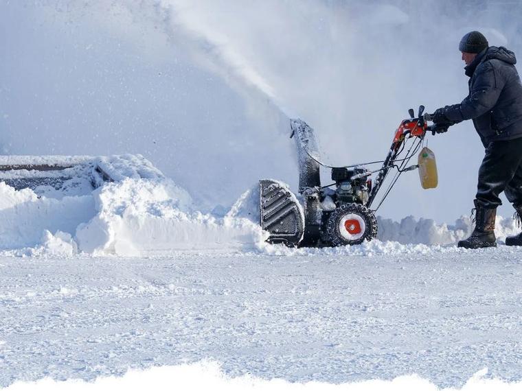 Operator clearing deep snow from a Green Bay driveway with a two-stage snow blower